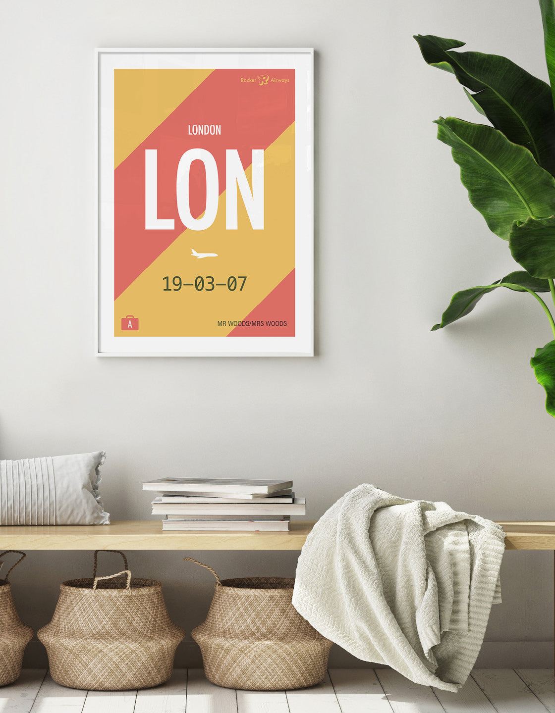 image showcasing the print on the wall above a wooden bench seat with seagrass baskets and a palm leaf plant